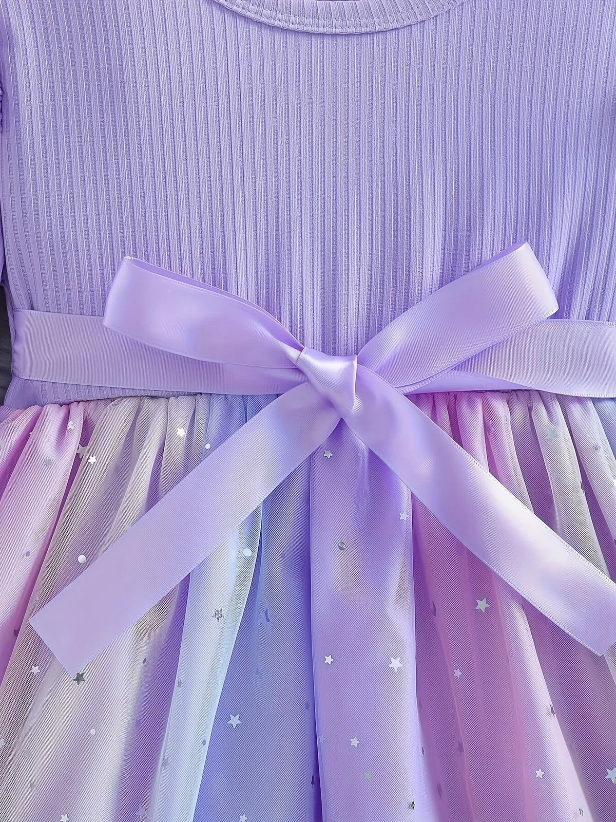 Close-up of the shimmering silver star print on the purple and blue gradient tulle skirt with a satin bow.
