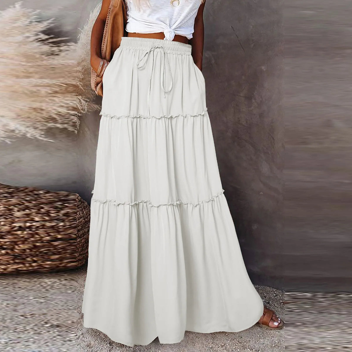 Woman wearing a white floor-length tiered maxi skirt with a high-waisted drawstring.